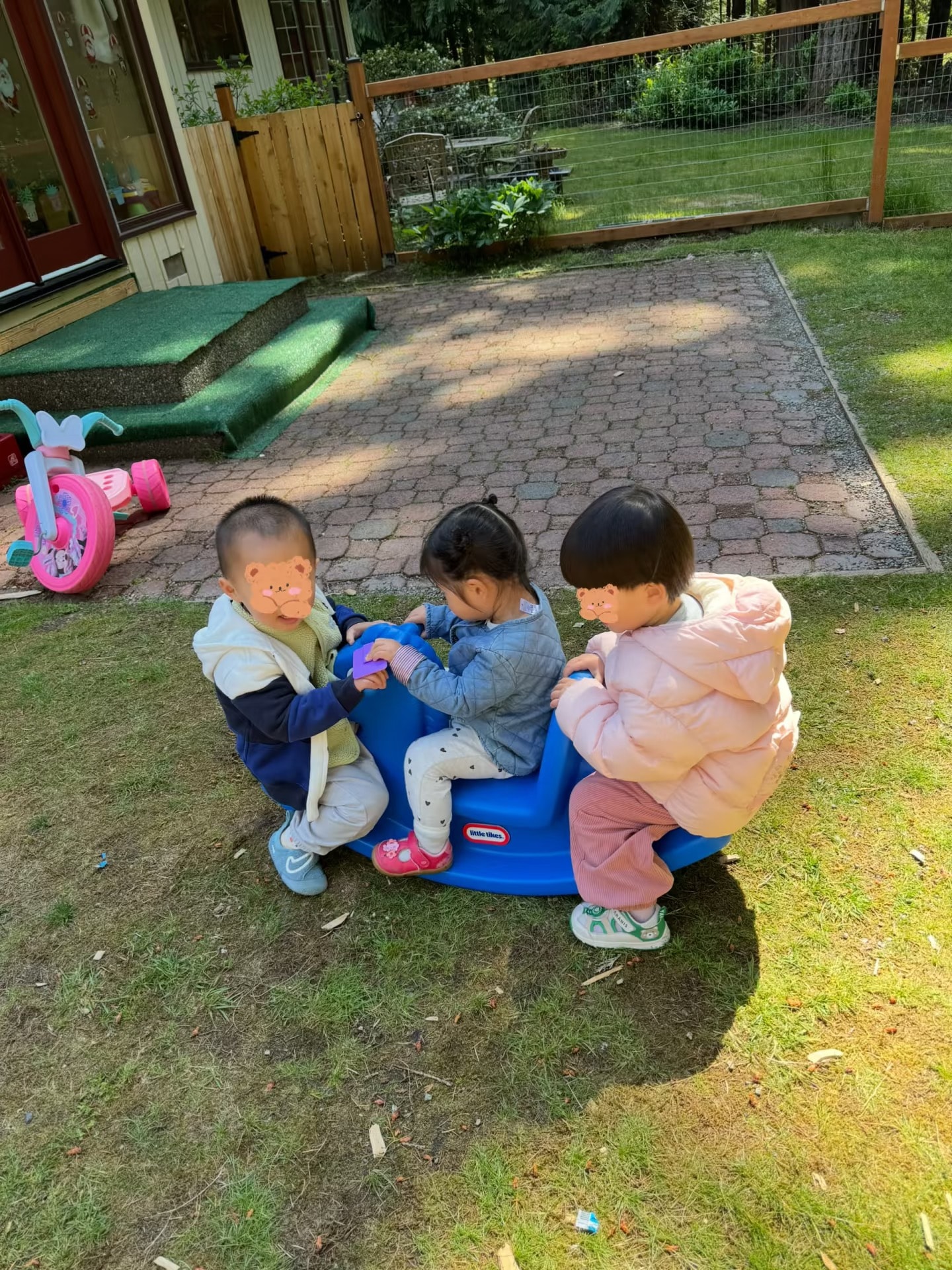 Panda Bear Childcare — three toddlers playing on toy in backyard