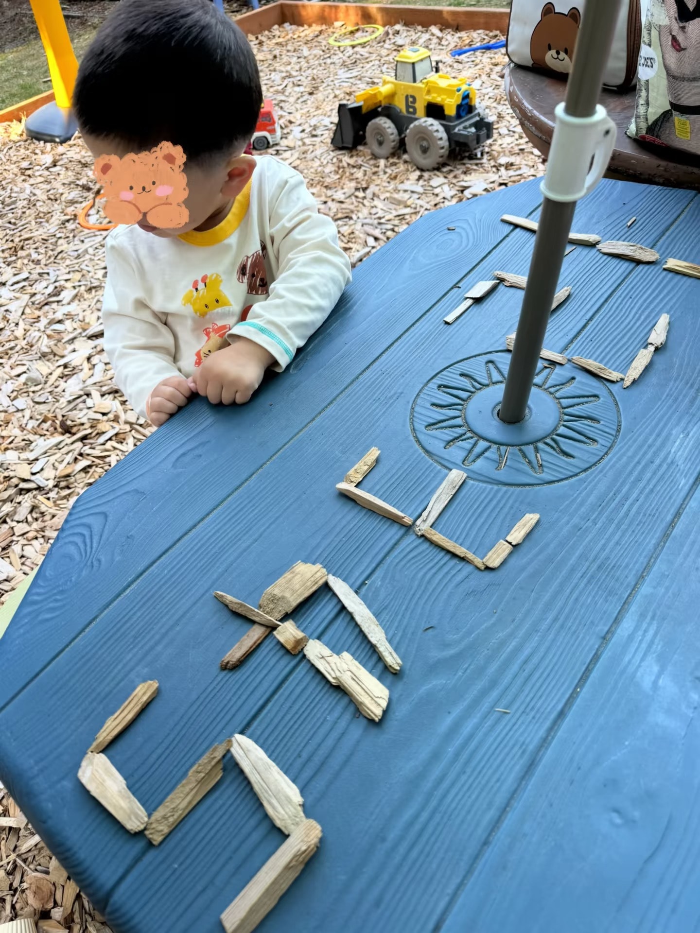 Panda Bear Childcare — toddler playing with sticks outdoor sensory table