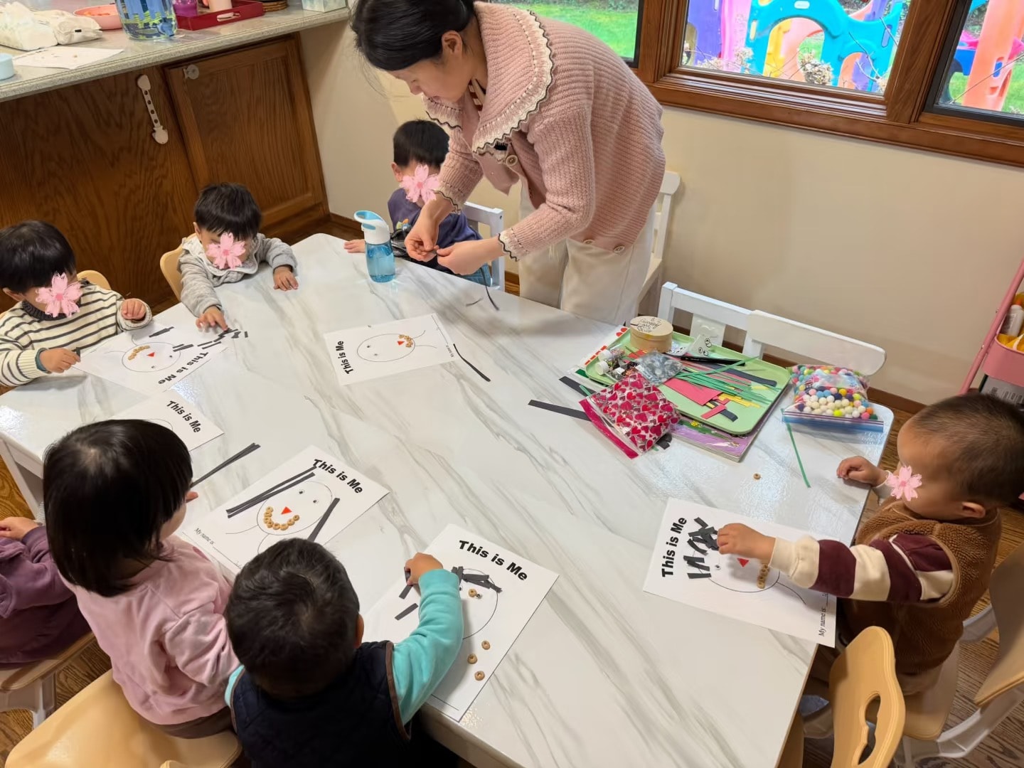 Panda Bear Childcare — teacher guiding young children art class activity